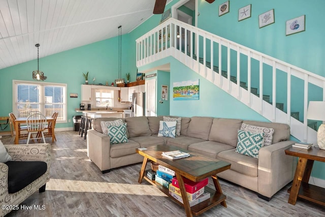 living room featuring high vaulted ceiling, sink, and light hardwood / wood-style floors