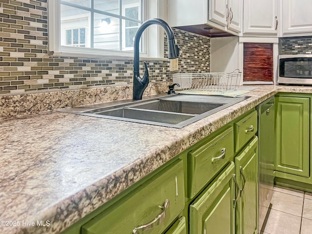 kitchen featuring light tile patterned floors, green cabinets, tasteful backsplash, white cabinets, and sink