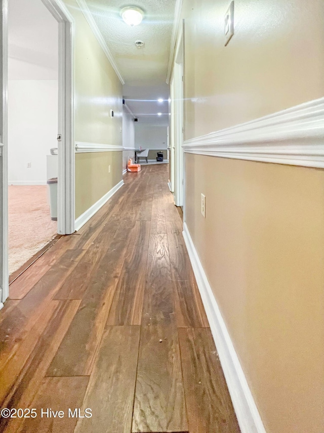 hallway featuring a textured ceiling, ornamental molding, and wood-type flooring