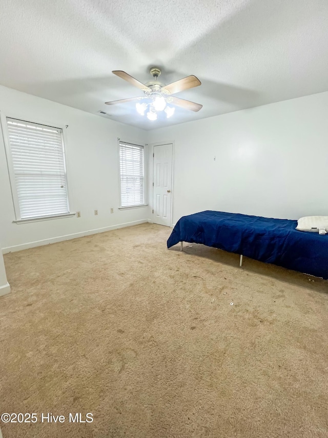 bedroom featuring ceiling fan, light colored carpet, and a textured ceiling