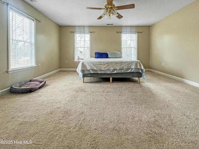 carpeted bedroom with ceiling fan, multiple windows, and a textured ceiling