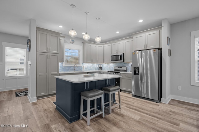 kitchen with a sink, decorative backsplash, light countertops, appliances with stainless steel finishes, and a kitchen island