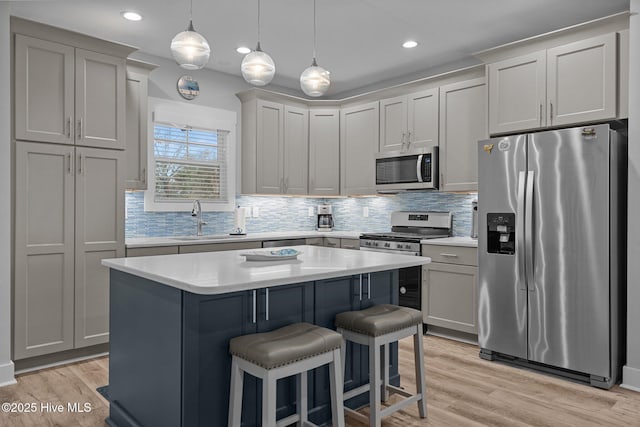 kitchen with a sink, decorative backsplash, stainless steel appliances, a kitchen bar, and a kitchen island