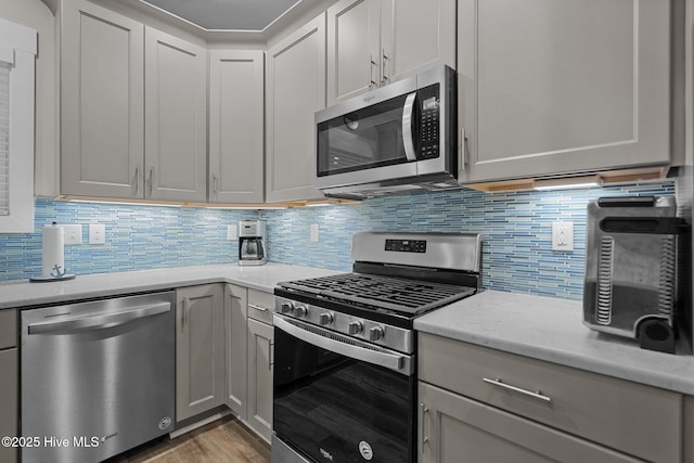 kitchen with backsplash, light stone counters, stainless steel appliances, and light wood-type flooring