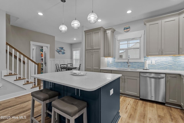 kitchen featuring dishwasher, gray cabinets, a center island, and a sink
