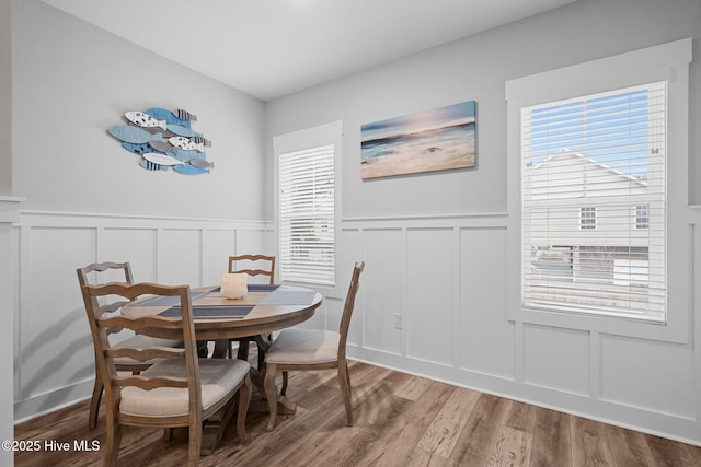 dining room with wainscoting, a decorative wall, and wood finished floors