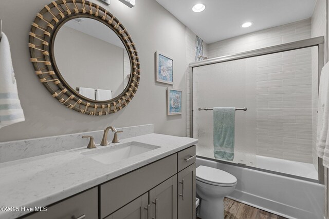 245 NE 64th St, Oak Island, NC 28465 - bathroom featuring vanity, wood finished floors, shower / bath combination with glass door, and recessed lighting