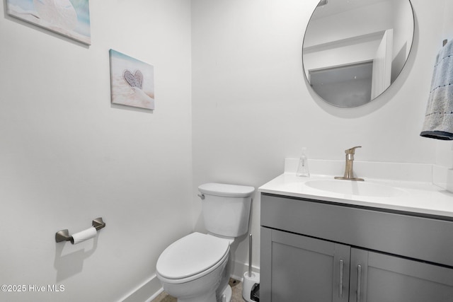 bathroom with vanity, toilet, and baseboards
