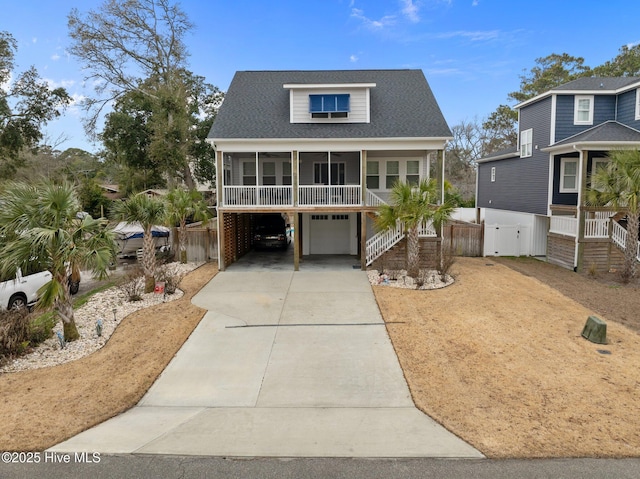 raised beach house featuring a garage, driveway, and stairs