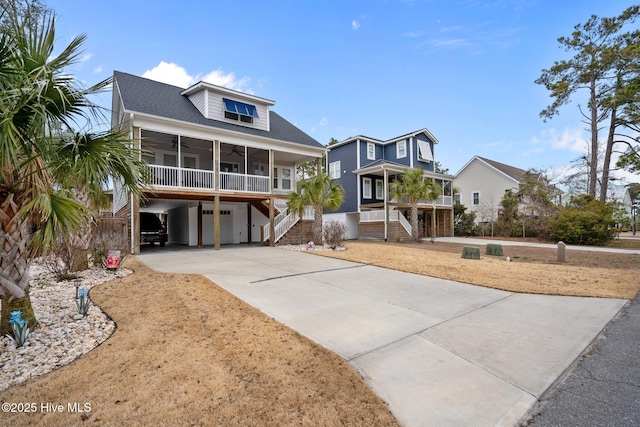 beach home featuring stairway, driveway, a carport, a ceiling fan, and a garage