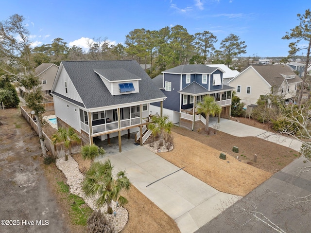 view of front of property featuring a residential view, concrete driveway, covered porch, a carport, and roof with shingles