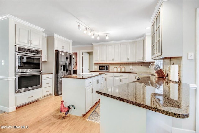 kitchen featuring appliances with stainless steel finishes, crown molding, white cabinets, and dark stone counters