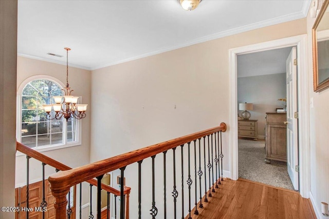 hall featuring light hardwood / wood-style floors, ornamental molding, and a chandelier