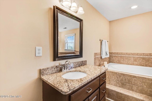 bathroom with vanity and tiled tub