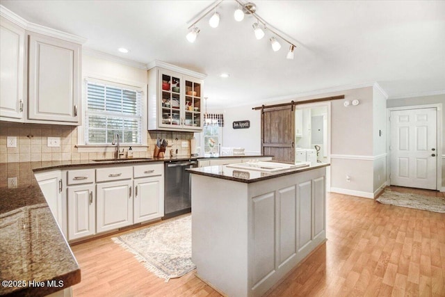 kitchen with stainless steel dishwasher, a barn door, sink, and white cabinets