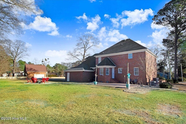 back of property with a garage, central air condition unit, and a lawn