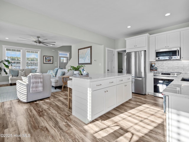 kitchen featuring stainless steel appliances, light hardwood / wood-style floors, white cabinets, and a center island