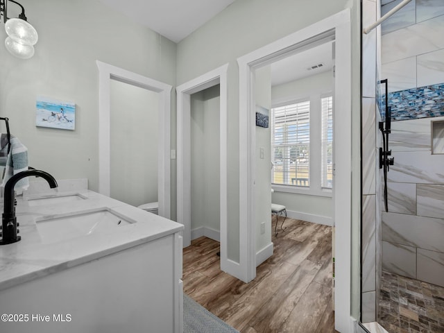 bathroom featuring hardwood / wood-style flooring, tiled shower, and vanity