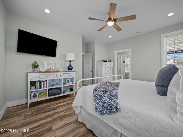 bedroom featuring ceiling fan, hardwood / wood-style floors, and multiple windows