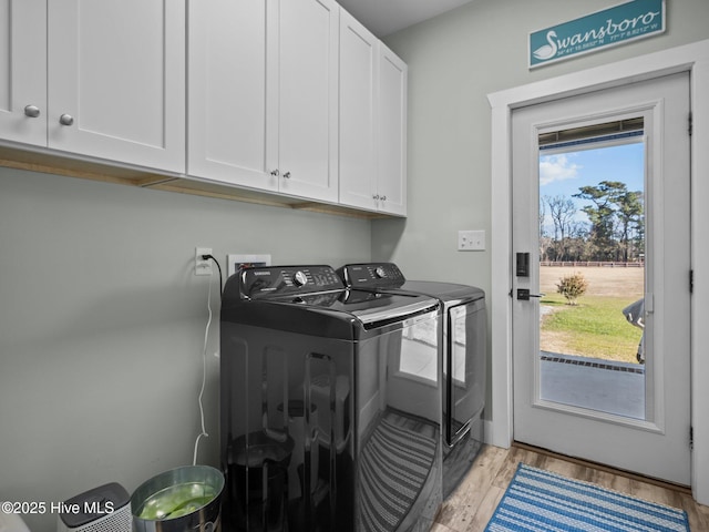 laundry room with light wood-type flooring, cabinets, and washing machine and clothes dryer