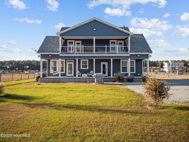 back of property featuring a lawn, a balcony, and covered porch