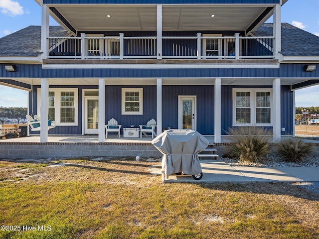 view of front facade featuring a front lawn, a patio area, and a balcony