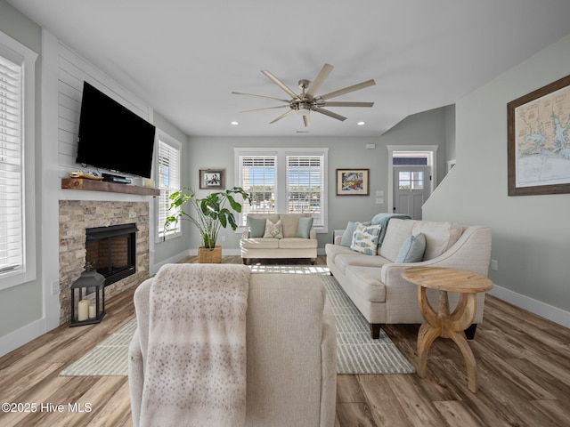 living room featuring ceiling fan, light wood-type flooring, and a fireplace