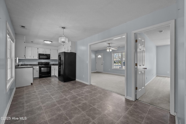 kitchen featuring decorative light fixtures, black appliances, a textured ceiling, dark carpet, and white cabinets