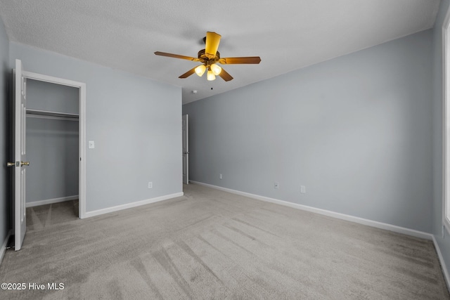 unfurnished bedroom with a walk in closet, ceiling fan, light carpet, a textured ceiling, and a closet