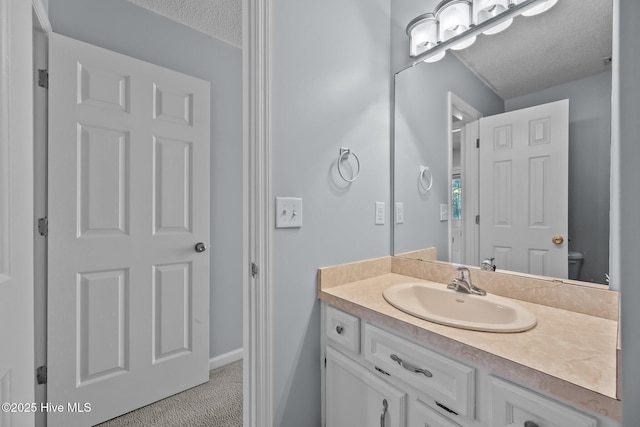 bathroom featuring vanity, a textured ceiling, and toilet