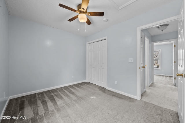 unfurnished bedroom with ceiling fan, a closet, light carpet, and a textured ceiling