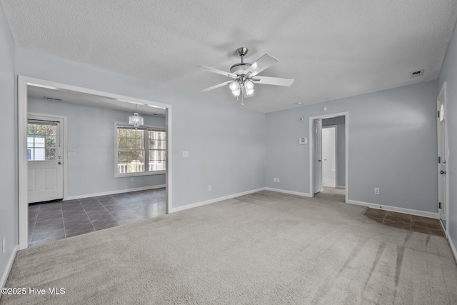 empty room featuring ceiling fan with notable chandelier, a textured ceiling, and dark colored carpet