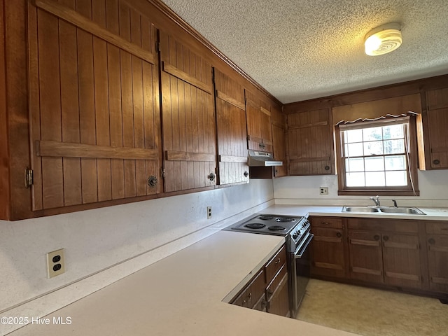 kitchen featuring stainless steel electric range, sink, and a textured ceiling