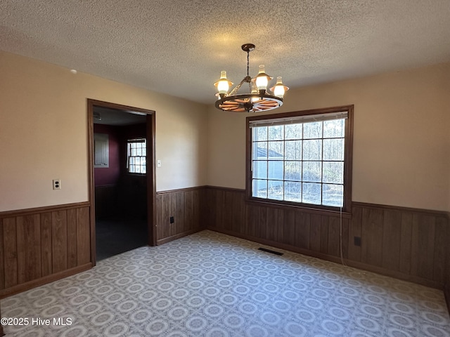 unfurnished room featuring a textured ceiling and an inviting chandelier