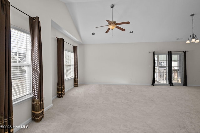 carpeted empty room with lofted ceiling and ceiling fan with notable chandelier