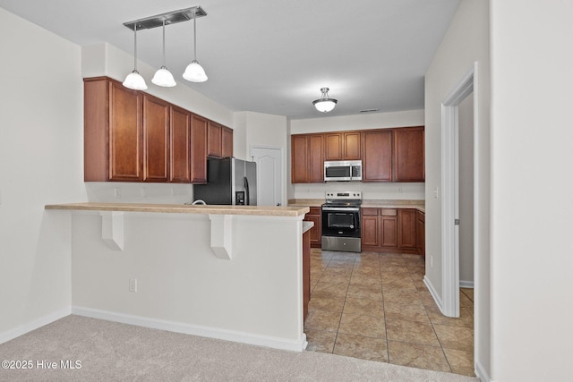 kitchen featuring pendant lighting, kitchen peninsula, appliances with stainless steel finishes, a kitchen breakfast bar, and light tile patterned floors