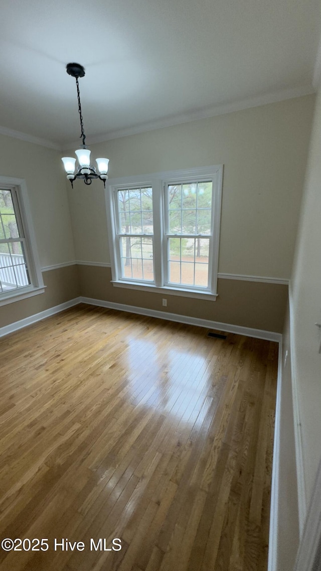 unfurnished room featuring hardwood / wood-style flooring, ornamental molding, and an inviting chandelier