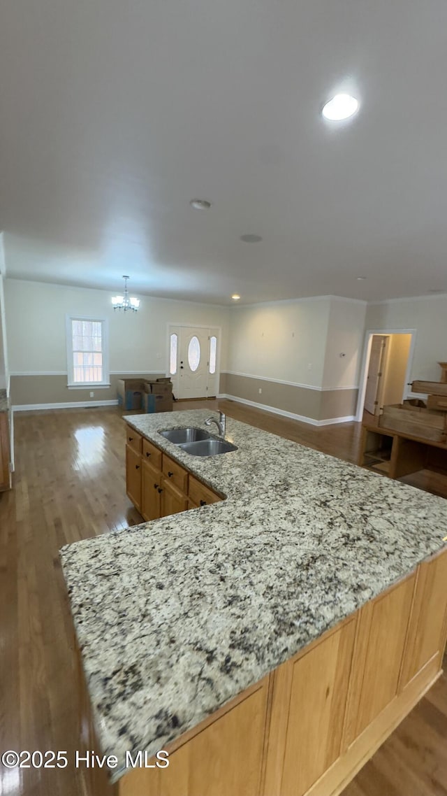 kitchen with an inviting chandelier, sink, light stone counters, and hardwood / wood-style flooring