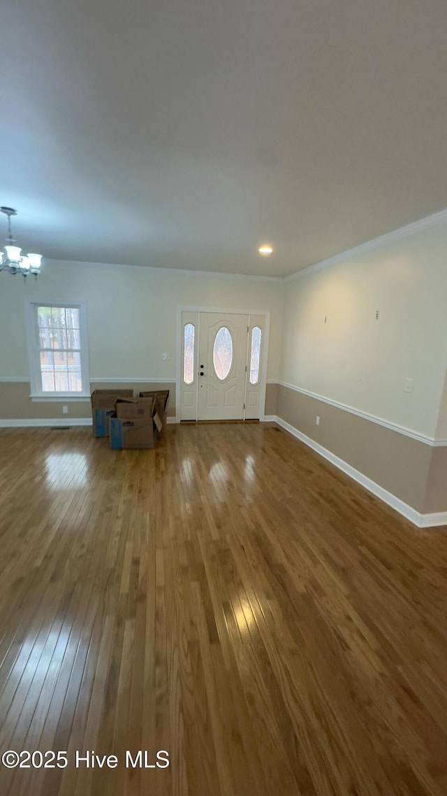 unfurnished living room featuring wood-type flooring and an inviting chandelier