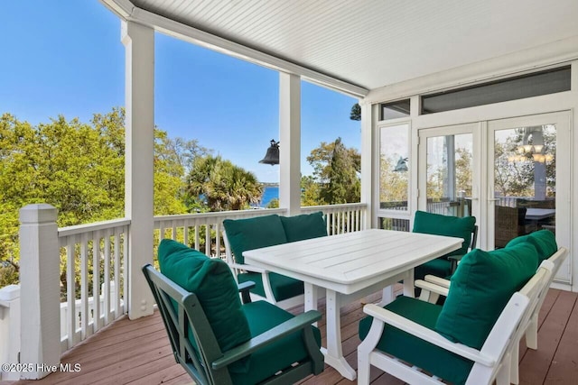 sunroom / solarium featuring a water view and french doors