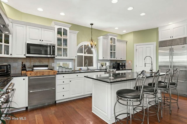 kitchen featuring a notable chandelier, stainless steel appliances, white cabinetry, and decorative light fixtures