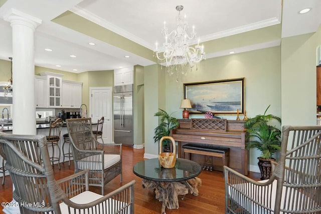 sitting room featuring ornate columns, sink, ornamental molding, a chandelier, and hardwood / wood-style flooring