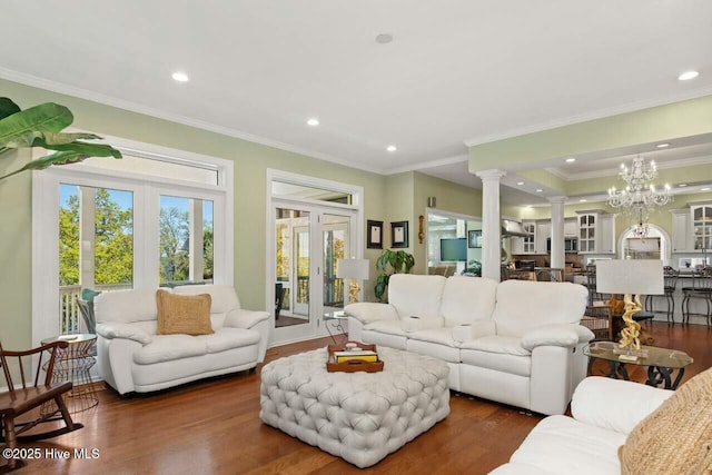 living room with ornate columns, dark hardwood / wood-style flooring, crown molding, and a notable chandelier