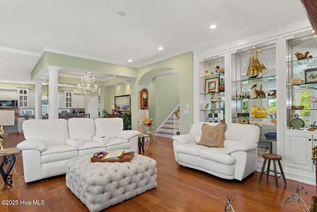 living room with hardwood / wood-style flooring, built in features, ornamental molding, and a chandelier