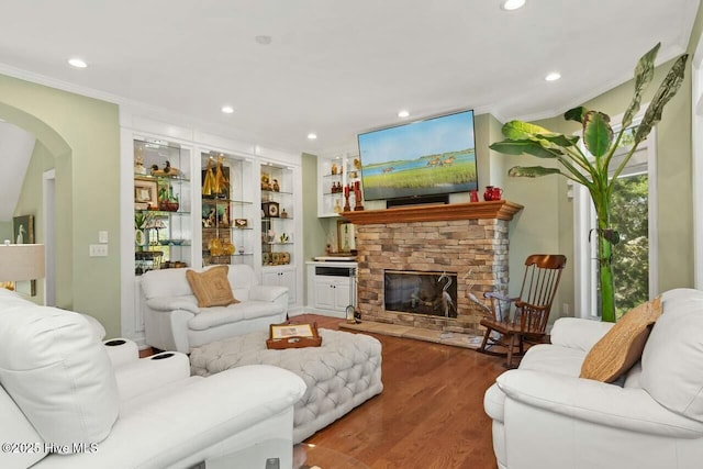 living room featuring wood-type flooring, crown molding, and a fireplace