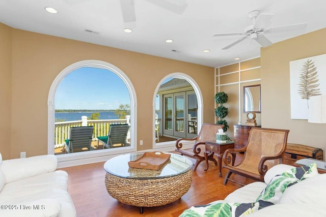 living room with a water view, ceiling fan, and hardwood / wood-style flooring