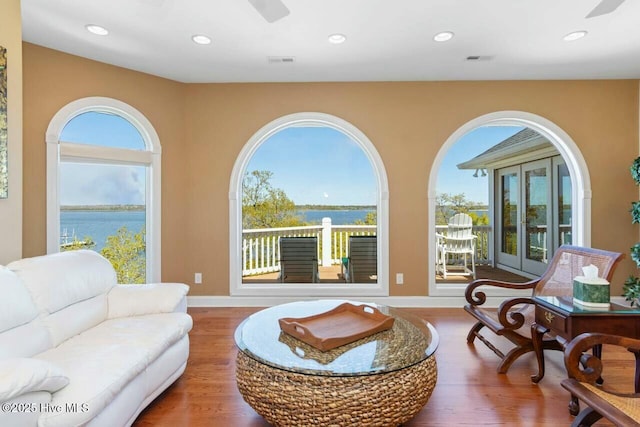 living room with hardwood / wood-style flooring, ceiling fan, and a water view