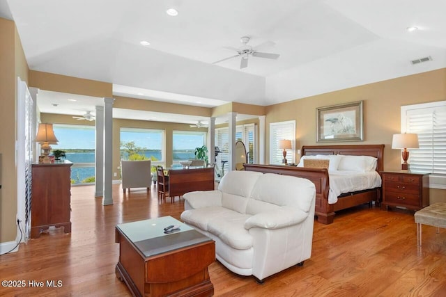 bedroom with ceiling fan, a tray ceiling, access to outside, and light wood-type flooring