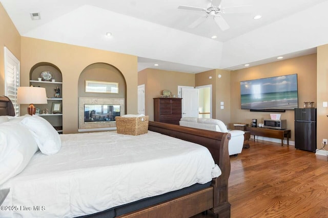 bedroom featuring ceiling fan, black refrigerator, wood-type flooring, and lofted ceiling