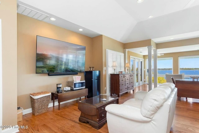 living room featuring light wood-type flooring, lofted ceiling, and decorative columns